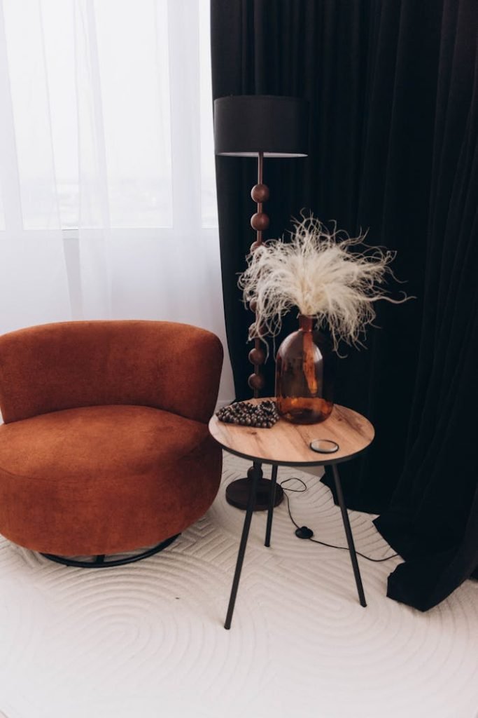 Stylish lounge featuring a brown armchair, sleek lamp, and decorative vase on a small table.