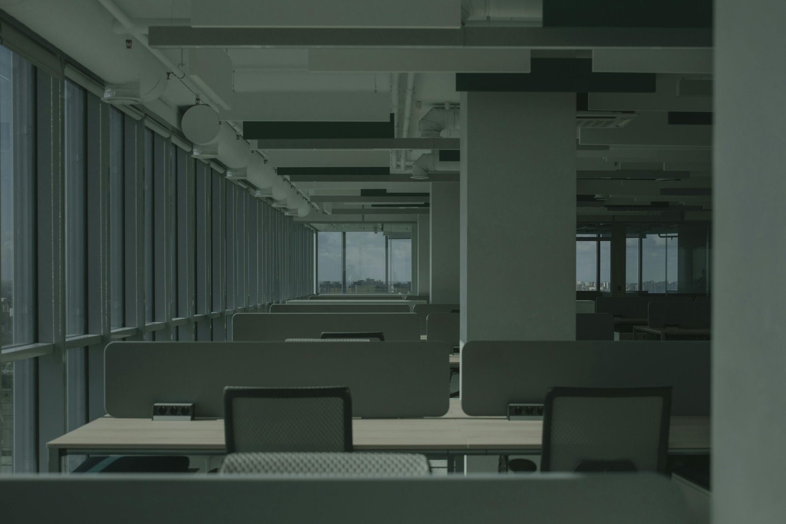 Spacious empty office with rows of desks and large windows.